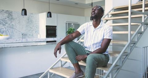 Man Relaxing on Stylish Staircase in Modern Minimalist Kitchen