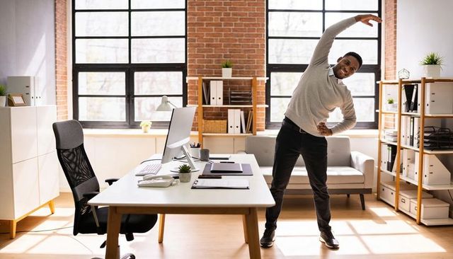 Male office worker stretching in bright industrial loft for employee wellness