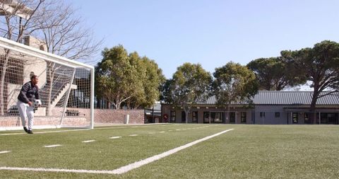 Lone goalkeeper on soccer field under clear blue sky