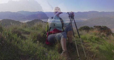 Mature hiker resting on grassy hillside with scenic view