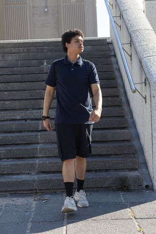 Young african american man walking down urban stairs carrying backpack in daylight