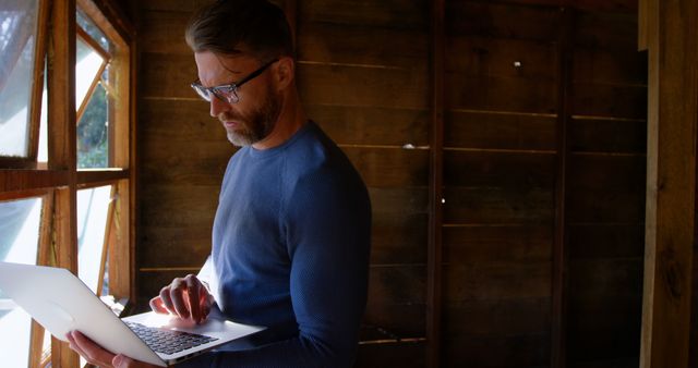 Man Working on Laptop in Rustic Wooden Interior with Sunlight - Download Free Stock Images Pikwizard.com