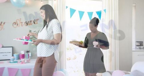 Expectant woman serving cupcakes at pastel baby shower with friends and decorations