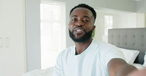 African American Man Smiling on Bed in Modern Bedroom for Self-Care