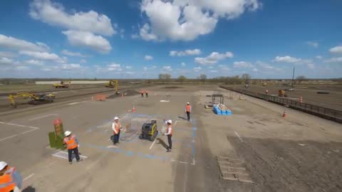 Construction Crew Preparing Marked Work Zone and Roller After Safety Briefing on Open Site