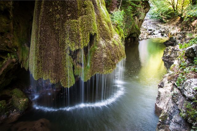 This picturesque waterfall cascades gently over moss-covered rocks within a verdant forest. Ideal for illustrating natural beauty, serenity, and outdoor adventures. Perfect for travel articles, nature blogs, and eco-friendly tourism promotions.