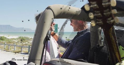 Mature men laughing in convertible at coastal turnout, sunny roadtrip and ocean views