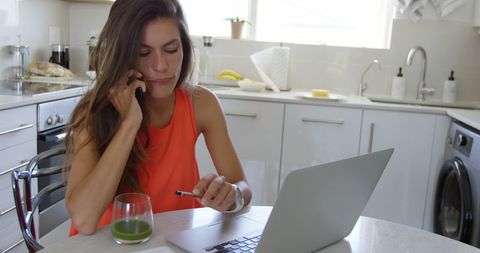 Woman working from home with laptop and healthy smoothie