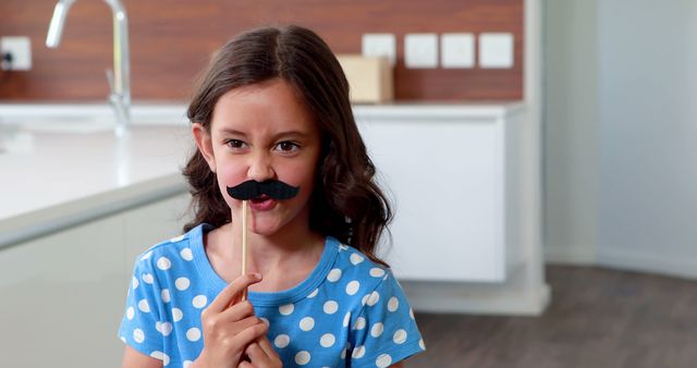 Girl Holding Fake Mustache Prop in Modern Kitchen - Download Free Stock Images Pikwizard.com