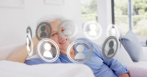Senior woman relaxing on sofa with floating social network icons representing connection