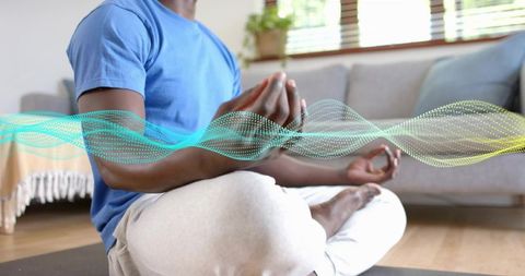 Meditating man practicing mindfulness at home with calming digital energy wave overlay