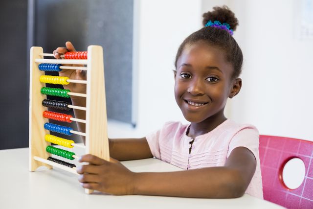 portrait of schoolgirl using a maths abacus in classroom at school
