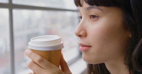 Contemplative Woman Sipping Coffee by Office Window
