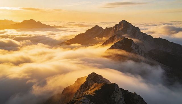 Sunlit Alpine Ridge Emerging Through Rolling Sea of Clouds at Golden Dawn Panorama