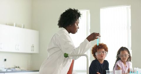 African american teacher demonstrating chemistry experiment to students in classroom lab