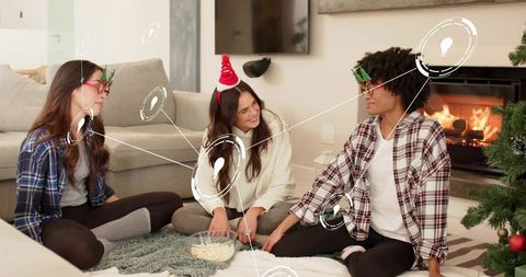 Friends sharing popcorn during cozy holiday movie night by fireplace in festive glasses