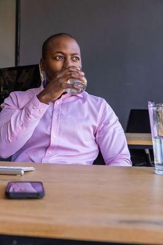 Professional Man in Pink Shirt Drinking at Office Desk