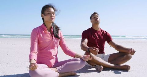 Couple Meditating on Sandy Beach Practicing Mindfulness and Deep Breathing Together by Sea