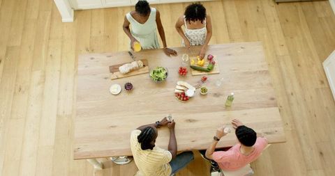 Friends Enjoying Meal Preparation Around Kitchen Table