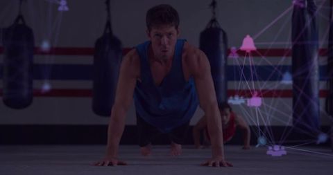 Man Holding Push-Up Position in Boxing Gym Setting