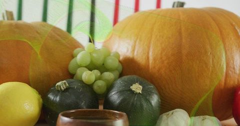 Autumn harvest still life featuring pumpkins, round green squash, grapes, lemon, garlic
