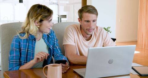 Couple Discussing Plans at Home with Laptop and Smartphone