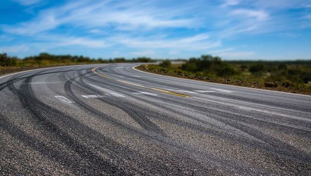 Winding rural asphalt road with skid marks and scenic views