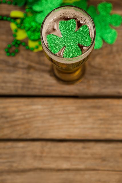 Glass of beer and shamrock for St Patricks Day on wooden background