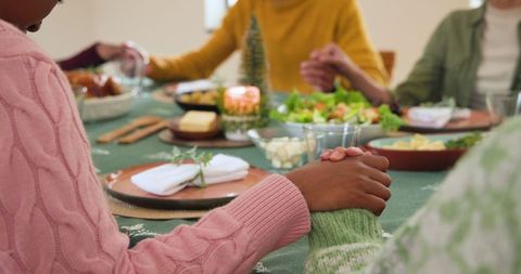 Family Holding Hands in Prayer During Festive Meal