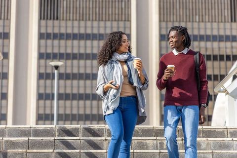 Diverse young professionals walking and chatting with coffee in urban business district