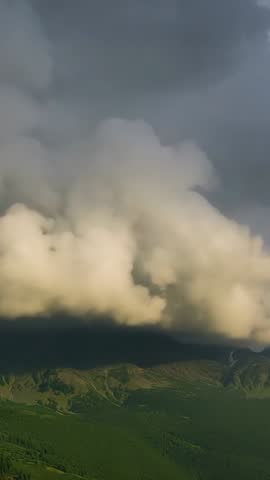 Sunlight Penetrating Storm Cloud Over Mountain Ridge Creating Dramatic Fog Vertical Video