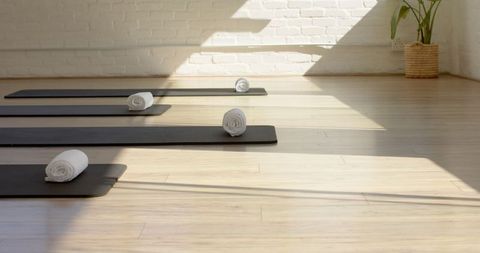 Sunlit Yoga Studio with Rolled Mats on Wooden Floor
