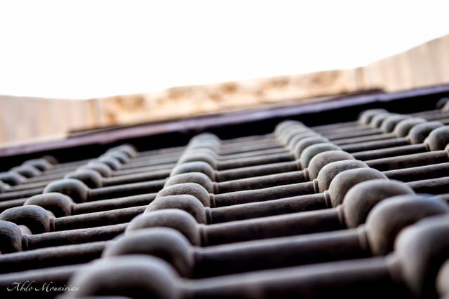Stock photo of metal grate taken from below looking upward with the sky in the background. Ideal for architectural projects, urban design concepts, industrial themes, or as a background in artistic compositions.