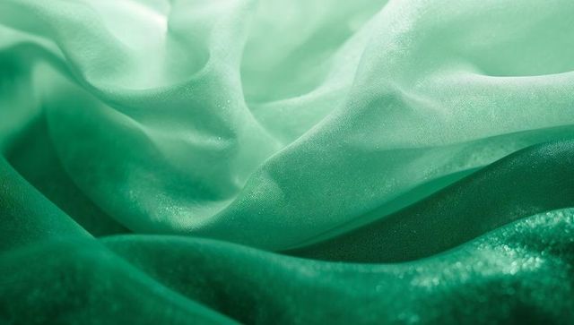 Layered green fabrics showing sheer mint chiffon draping over emerald velvet with shimmer