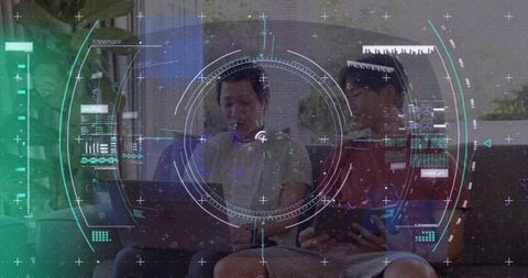 Man and teen collaborating on laptop with futuristic augmented hud overlay at home