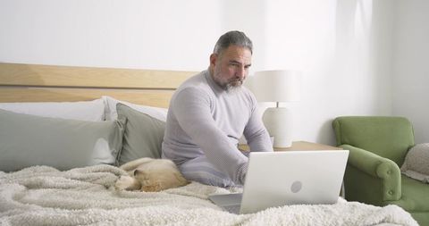 Bearded Man in Grey Loungewear Working on Laptop with Sleeping Dog