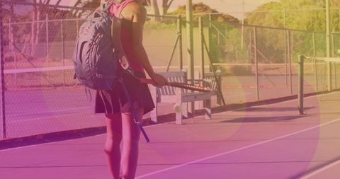 Tennis Player Walking with Racket and Backpack at Tennis Court