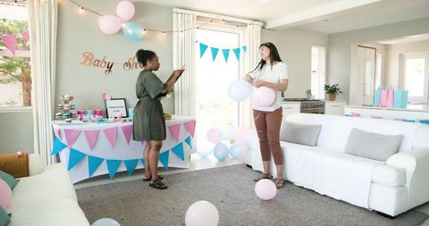 Two Friends Preparing Living Room for Vibrant Baby Shower Celebration