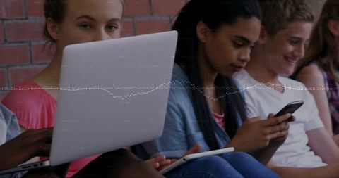 Teen students collaborating on laptops and smartphones with digital waveform overlay
