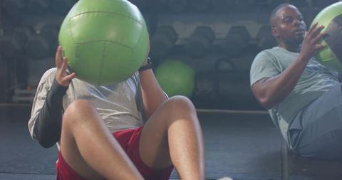 African american men doing russian twist with green med balls partner core workout