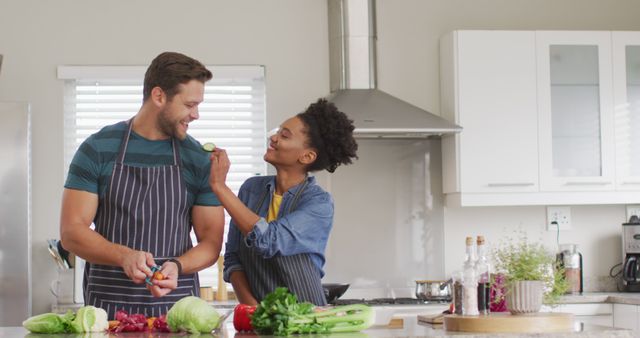 Image of happy diverse couple preparing meal, cutting vegetables in kitchen. Love, relationship and spending quality time together at home.