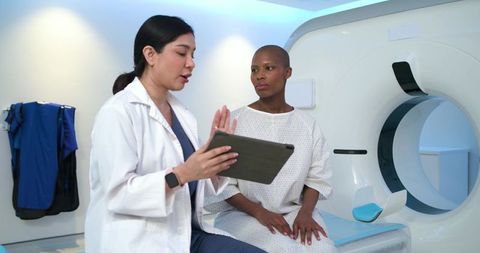 Female clinician explaining mri procedure to patient using tablet beside scanner