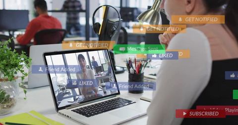 Young professional engaging in video call with social media notifications overlaying laptop