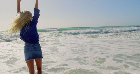 Joyful Woman Playing in Ocean Waves on Sunny Beach