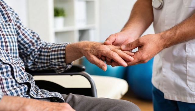 Nurse holding senior's hand during health check compassionate care for elderly patients