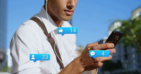 Young man checking smartphone with social media notifications on sunny urban street