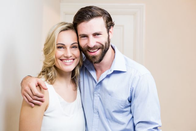 Couple smiling and embracing at home. Useful for content about relationships, love, family bonding, and positive lifestyle. Ideal for articles, blogs, and advertisements focused on happy living and domestic harmony.