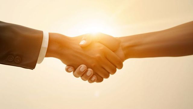 Sealing partnership with golden backlit handshake at sunset