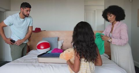 Family packing suitcase for vacation in cozy bedroom setting