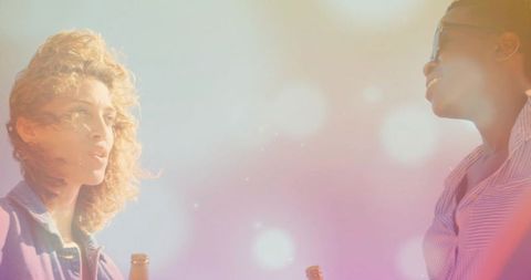 Joyful Friends Toasting with Bottles Outdoors in Vibrant Setting